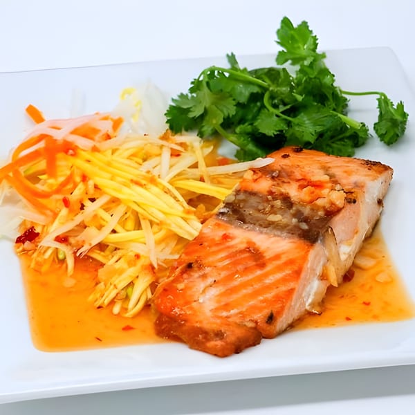 Belmarasia's grilled salmon with mango salad, chili sauce, and fresh cilantro on a white plate.